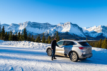 Man standing next to his SUV along the Icefields Parkway in Banff National Park, Canada