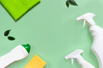 White spray bottle, cleansing gel, napkin and green leaves, sponge. The concept of ecological cleaning and cleaning of home and office. Green background. Middle text layout. view from above. Flat lay.