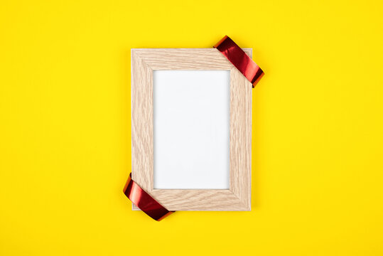 Wooden modern frame for a photo. On a yellow background mock up.