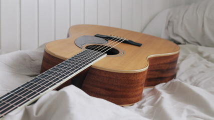Acoustic guitar on bed in the morning
