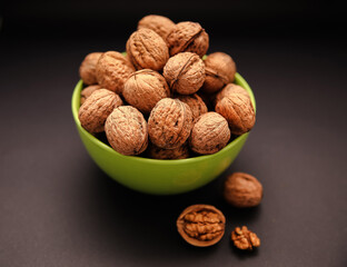 Walnuts in green bowl. Whole walnuts. Walnut kernel on black background. Walnut healthy food.