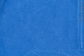 The texture of a cotton kimono for judo classes. Blue fabric close-up. The view from the top.