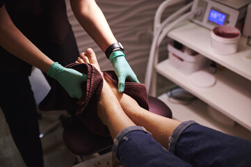 The pedicure master wipes the client's feet with a towel while making professional pedicure in...
