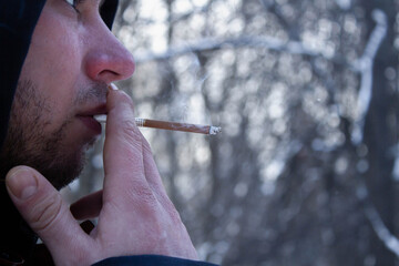 Man smoking cigarette outside in winter. Male hand