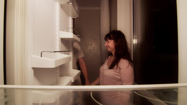 The family stands by the open refrigerator, they take a fresh cupcake from there