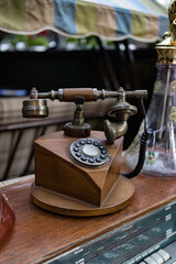 Old retro rotary phone is on the table, made of wood