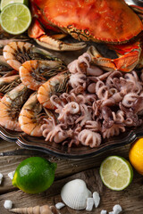 Macro shot of set of seafood. Cooked tiger shrimps, crab and baby octopuses with citrus on rustic wooden background. Healthy delicious food. Restaurants menu dish.