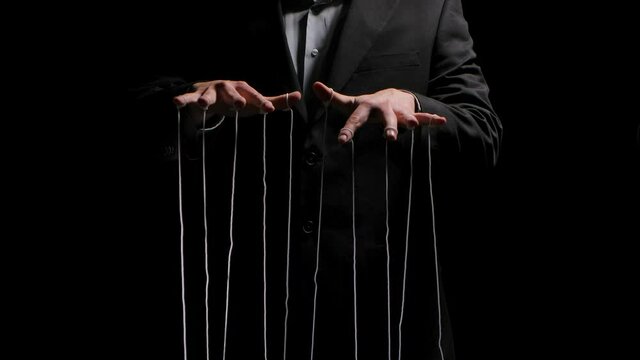Puppeteer pulls the doll strings tied to his fingers. Puppet rope manipulation concept and control hand. Businessman controls the mind and actions of people. Close up. Slow motion.