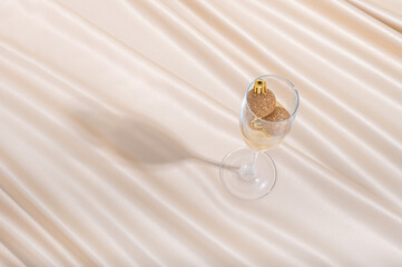 Creative minimal concept made of champaign glass and Christmas baubles on pastel silk sheet