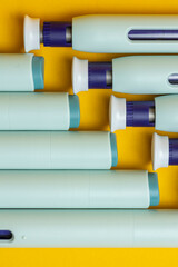 Top down closeup view of syringe injector pen on seamless yellow background. Studio medical equipment still life concept. © Maarten Zeehandelaar