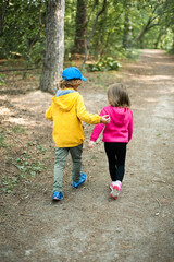Fototapeta premium Children in bright clothes walk in the forest.