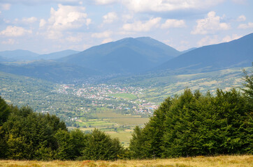 Beautiful landscape with forested hills and Carpathian village in the valley. Carpathian mountains in summer
