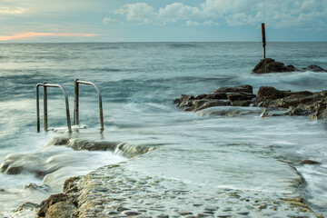 View of rustic handrailings ion a rocky bay during high tide
