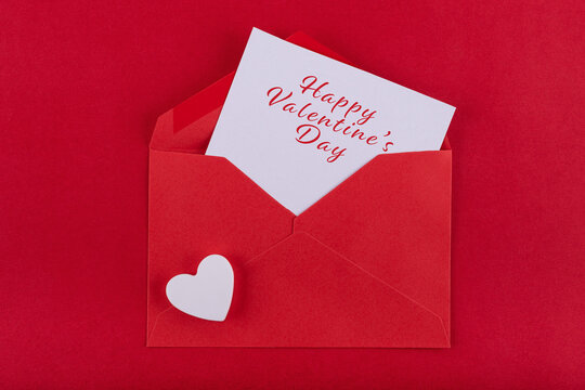 Red envelope containing a white card with a love message and white heart on a red background to congratulate Saint Valetin's day. Concept Valentine's day