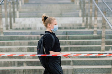 Schoolgirl in protective medical mask at sunset. Modern pupil with backpack during covid quarantine.