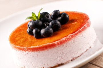 Plate with delicious blueberry cheesecake on light background