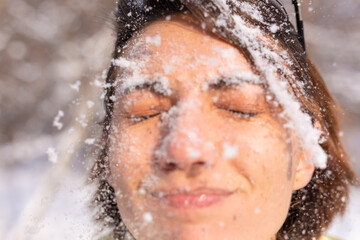 Portrait of a young woman in a winter forest on a sunny day with a snow-white smile, fooling around, all face in the snow