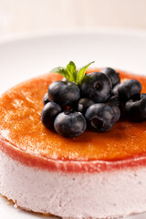 Plate with delicious blueberry cheesecake on light background