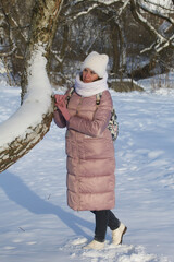 Woman in winter clothes on a walk in the park. There is a lot of snow around.