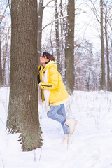 Beautiful young woman in the winter forest shows tender feelings for nature, shows her love for the tree, protect and take care of the environment concept