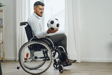 Young man in wheelchair holding football ball