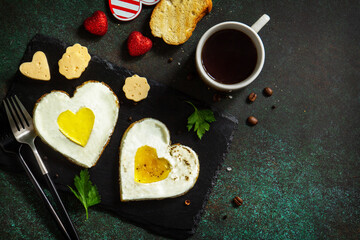 Breakfast on Valentines Day or brunch. Heart shape fried egg on slate plate.  Top view flat lay. Free space for your text.