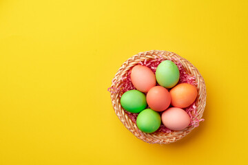 Fototapeta na wymiar Decorative nest with colorful Easter eggs on yellow background