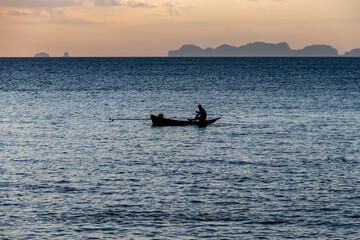 Fototapeta premium Pêcheur au coucher de soleil sur la mer à Koh Lanta, Thaïlande