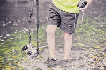 A child stands in the river on outdooor and destroys a mirrorless photo camera. The concept of...