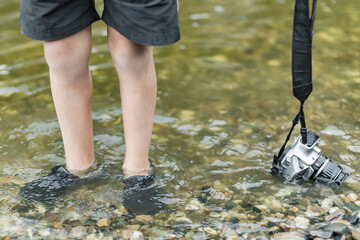 A schoolboy stands in the river on outdooor and destroys a mirrorless photo camera. The concept of...