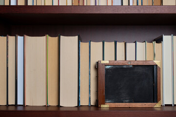Bookshelf with books displayed backwards and vintage film plate holder..
