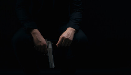 Close up of male hands holding weapon over black background. Gangster in suit holding gun in hands. Criminal lifestyle.