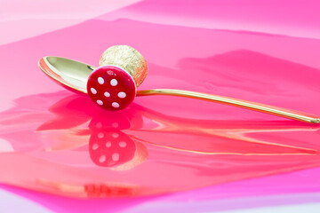 Concept for a lucky, prosperous life. Chocolate candy with toadstool hat on golden spoon as symbols of luck on red background