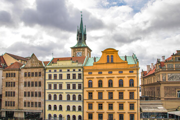 Colourful building facades in Prague Old Town with clock tower and steeples in background nobody