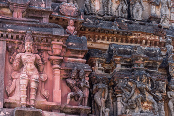 Fototapeta na wymiar Hampi, Karnataka, India - November 5, 2013: Vijaya Vitthala Temple. Closeup of blackened and damaged statues on red stone Gopuram.