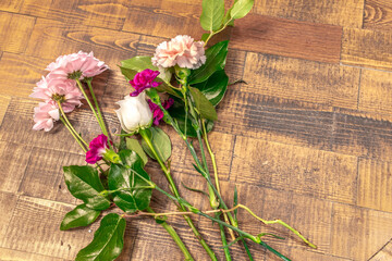 Closeup top view of blossom flowers with fresh green leaves lay on a wooden table surface. Arranging white rose and pink florals for decoration on a special day. Happy romantic love concept.