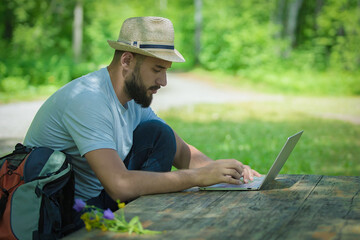 Obraz premium A young freelancer working on laptop outdoors sitting at the wooden antique desk. Concept of travel, business.