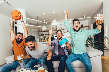 Naklejka premium Happy male friends wearing black face protective mask watching basketball at home