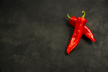 Two red peppers on a black background.
