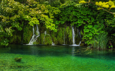 Closeup on green mossy hill with small waterfalls or cascades of water falling in to pond. Plitvice Lakes National Park UNESCO World Heritage, Croatia