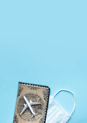 Fototapeta na wymiar on a blue background lies a passport in a beautiful cover with a vintage drawing of a map of the earth, a white airplane and a blue medical mask