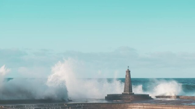 Storm waves crash against a lonely lighthouse in the open ocean