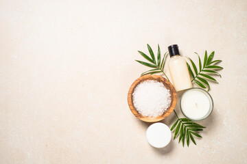 Fototapeta na wymiar Spa background. Spa product composition with palm leaves, cosmetic and sea salt at stone table. Flat lay image.