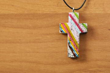 colorful christian cross on a wooden background with copy space