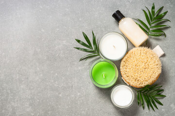 Fototapeta na wymiar Spa treatment background. Spa product composition with cosmetics, sea salt and palm leaves at stone table. Flat lay image with copy space.