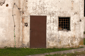 Building with rusted metal door and barred window. Rzeczyca Poland
