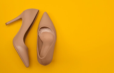 Two womens shoes stand on a yellow background with a large copy space