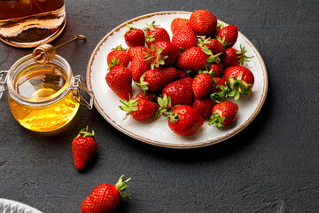 Plate with fresh strawberry and glass of wine on black background
