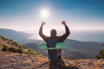 Male tourist with a backpack on the top of the mountain at sunrise