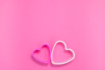 Pink and white heart shape cookie molds on pastel pink background. Elements for your romantic greeting card with copy space.